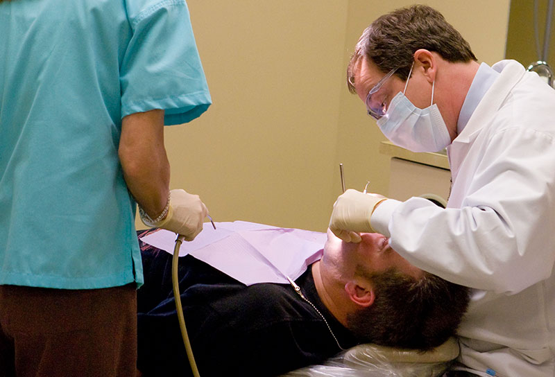 Photo of dentist cleaning a dental patient's teeth
