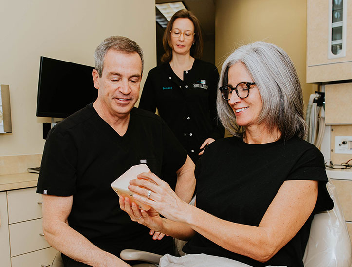 Photo of dental hygeinst showing patient how to properly brush teeth